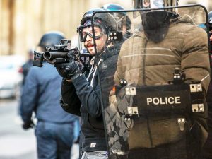 Zwei Polizeibeamte benutzen ein Schutzschild bei der Bekämpfung von Unruhen.